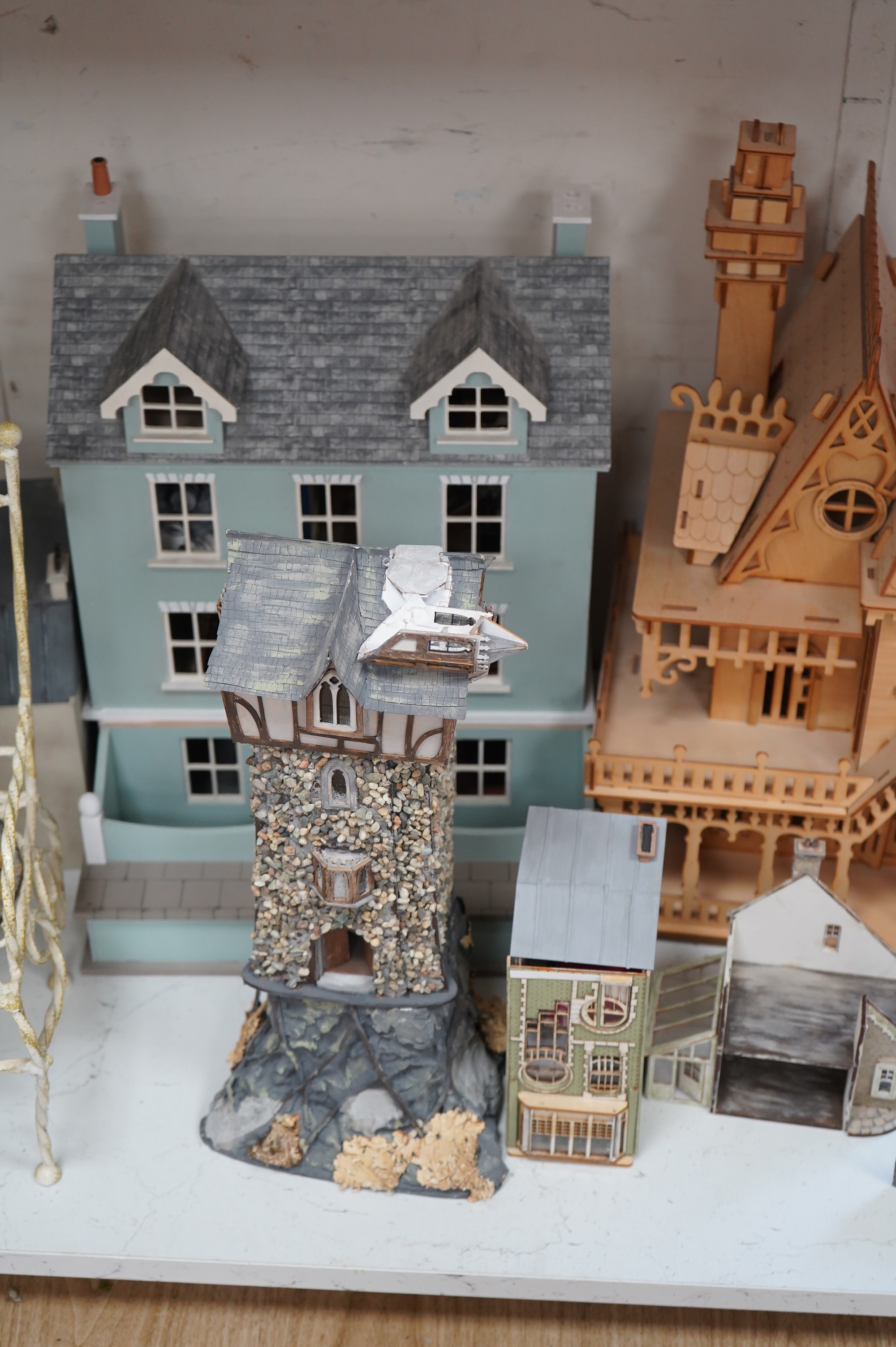 A modern plywood slot together model of a chateau, 50cm high, together with six miniature doll’s houses, a miniature wrought iron garden bench and chair set, and three miniature wooden chairs. Condition - fair.